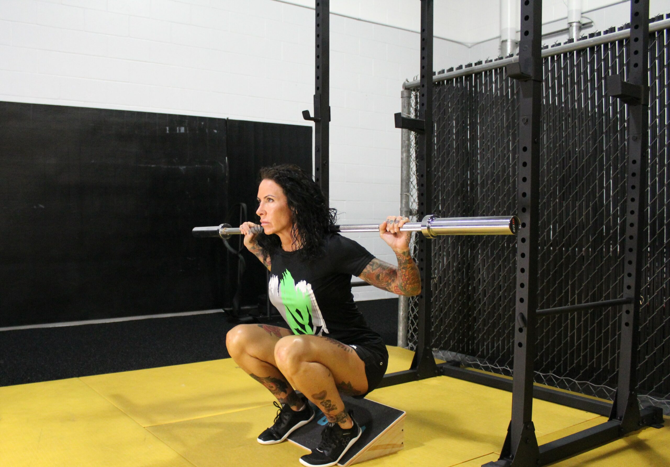 woman doing squat with lifted heels and weight bar